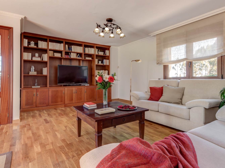 Salón de estética clásica, con mueble librería de madera y sofás beige_rojo como color de acento