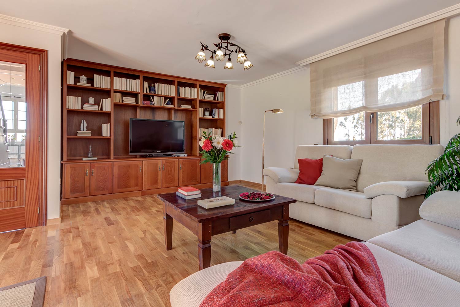 Salón de estética clásica, con mueble librería de madera y sofás beige_rojo como color de acento