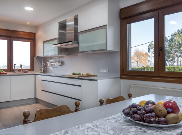 Cocina actual blanca con detalles clásicos_ Fruta sobre la mesa_Home Staging_ La ventana nos da una idea del paisaje exterior