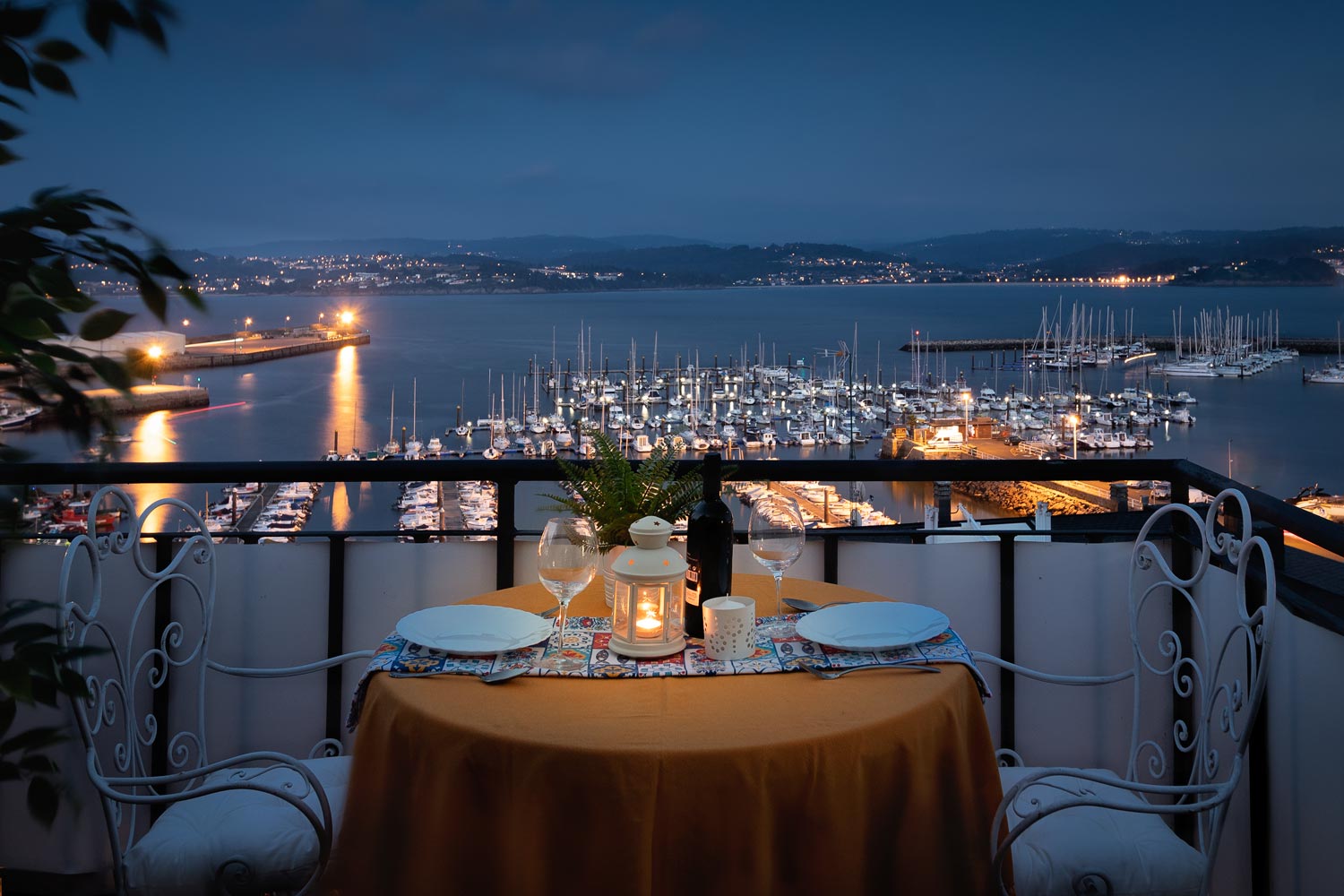 Peparación de mesa para cena en fotografía nocturna_ terraza superior de unifamiliar Sada y sus contornos_ vistas al puerto deportivo