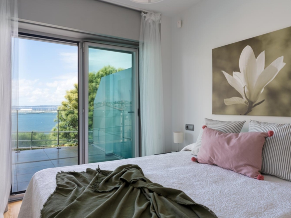 Dormitorio principal en bajo Costa Dulce Sada cojín rosa y manta verde_ventanal con puerta abatible y vistas al mar