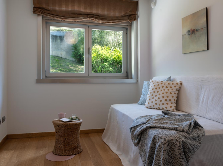 Dormitoirio individual en bajo Costa Dulce Sada_ cojjines verdes y blanco con puntos ocre_mesita de ratán_ventana