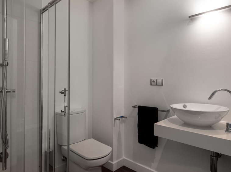 Cuarto de baño planta primera vivienda unifamiliar Oleiros_ Ducha, wc y lavabo sobre encimera con grifería moderna