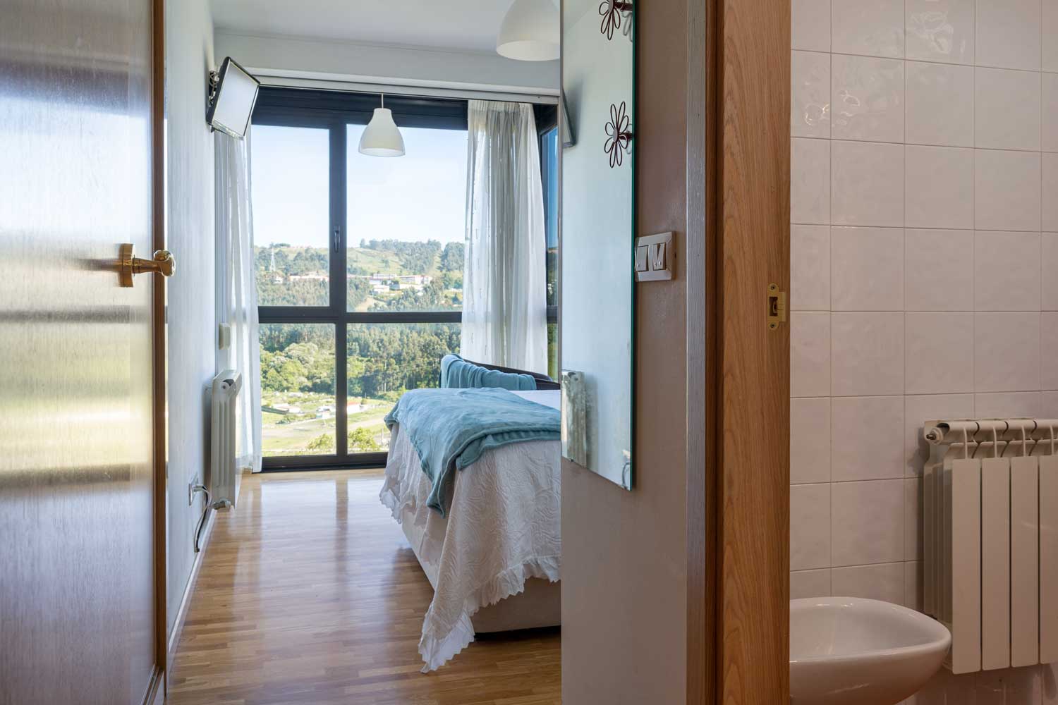 Dormitorio doble con baño en suite_ Textiles neutros y azules para home staging_ gran ventanal con vistas a paisaje