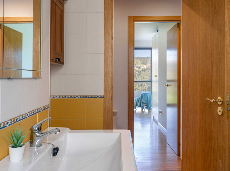 Cuarto de baño blanco y amarillo sencillo y conexión con dormitorio