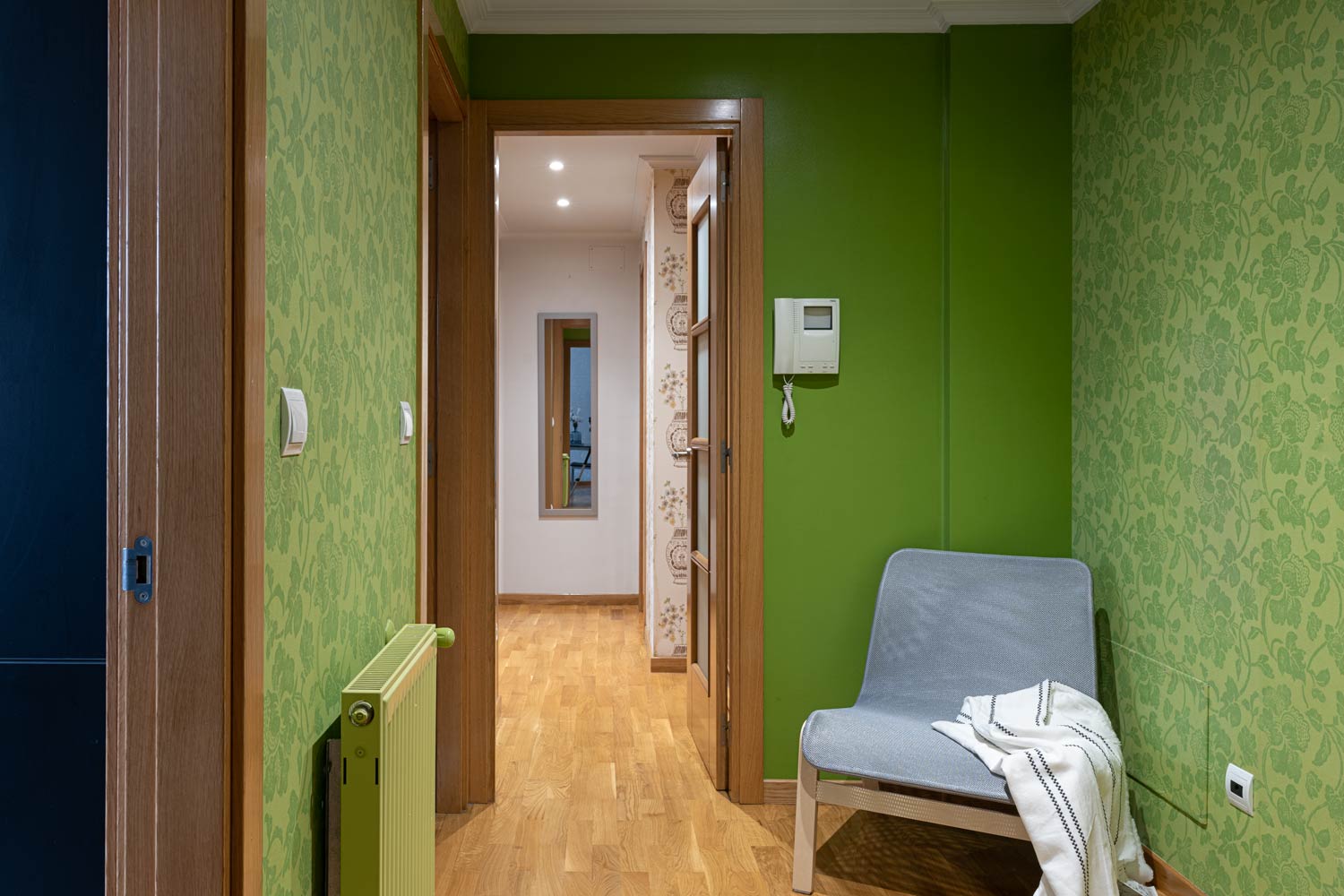 Recibidor en piso Rúa Betanzos_pintura y papel pintado verdes + silla_ Al fondo, el pasillo de las habitaciones y un espejo
