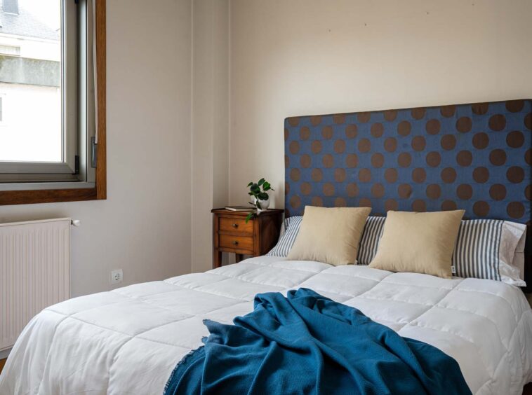 Dormitorio principal en piso Rúa Betanzos_cama con cabecero azul de topos marrones