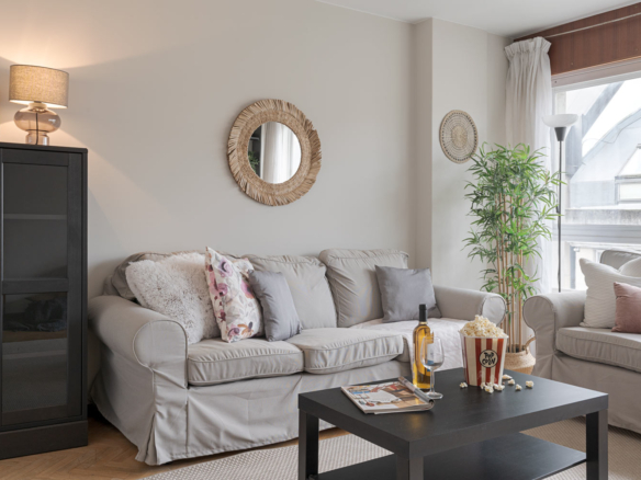 Acogedor salón de un piso en venta en Sada, A Coruña, decorado con un sofá gris, cojines, una planta de interior, invitando a la relajación y al confort hogareño preparado con Home Staging