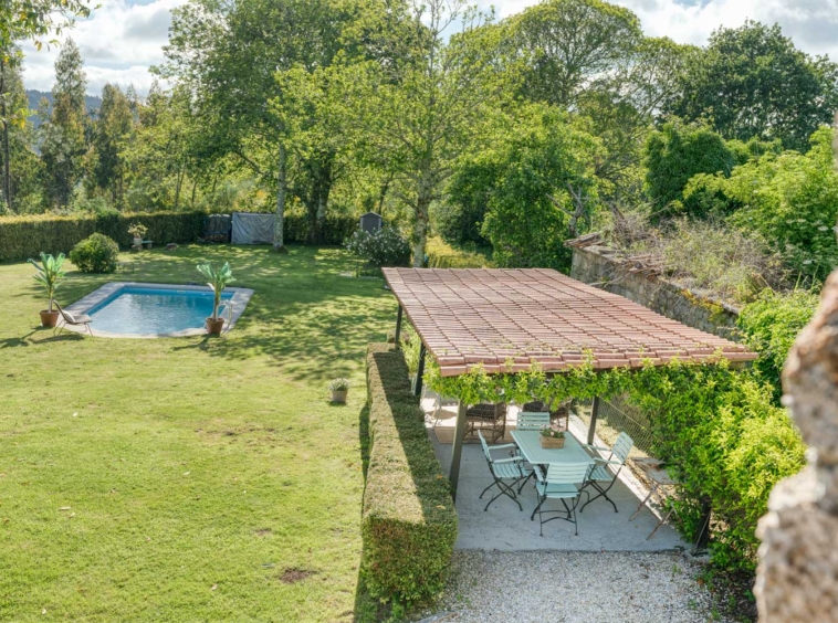 Vista aérea del jardín con piscina y zona de comedor al aire libre de una casa en venta en Aranga por Morando.