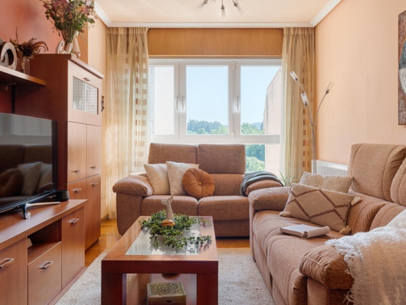 Sala de estar de un piso en venta en Sada por Inmobiliaria Morando, con sofás cómodos, mesa de centro de madera, mueble para TV y ventana grande que permite la entrada de luz natural.