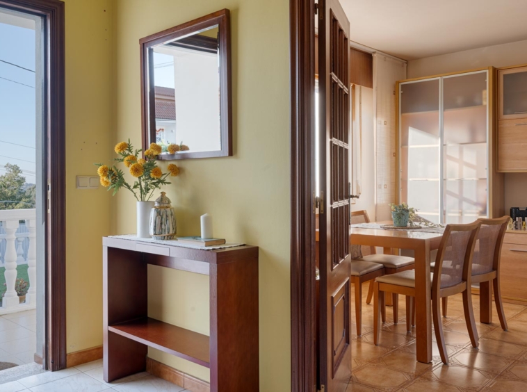 Entrada luminosa con recibidor de madera y flores amarillas en casa en venta en Sada por Inmobiliaria Morando.