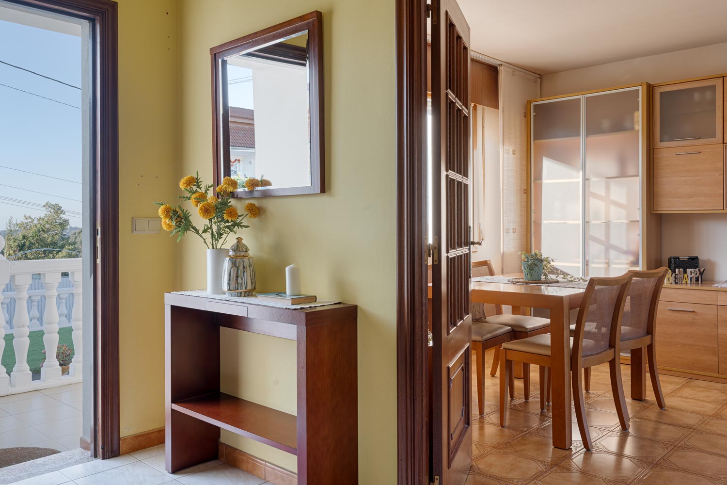 Entrada luminosa con recibidor de madera y flores amarillas en casa en venta en Sada por Inmobiliaria Morando.