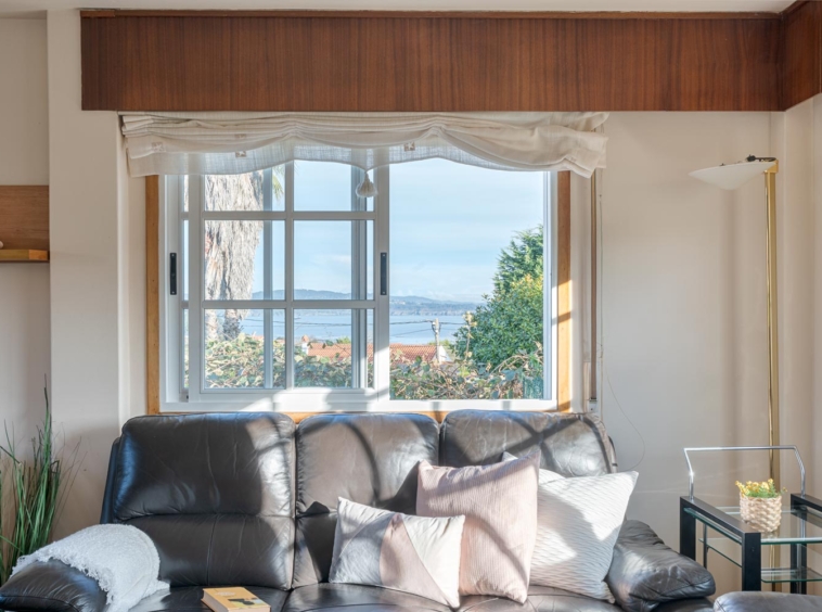 Sala de estar luminosa con sofás de cuero y ventana con vistas al mar en casa a la venta en Sada.