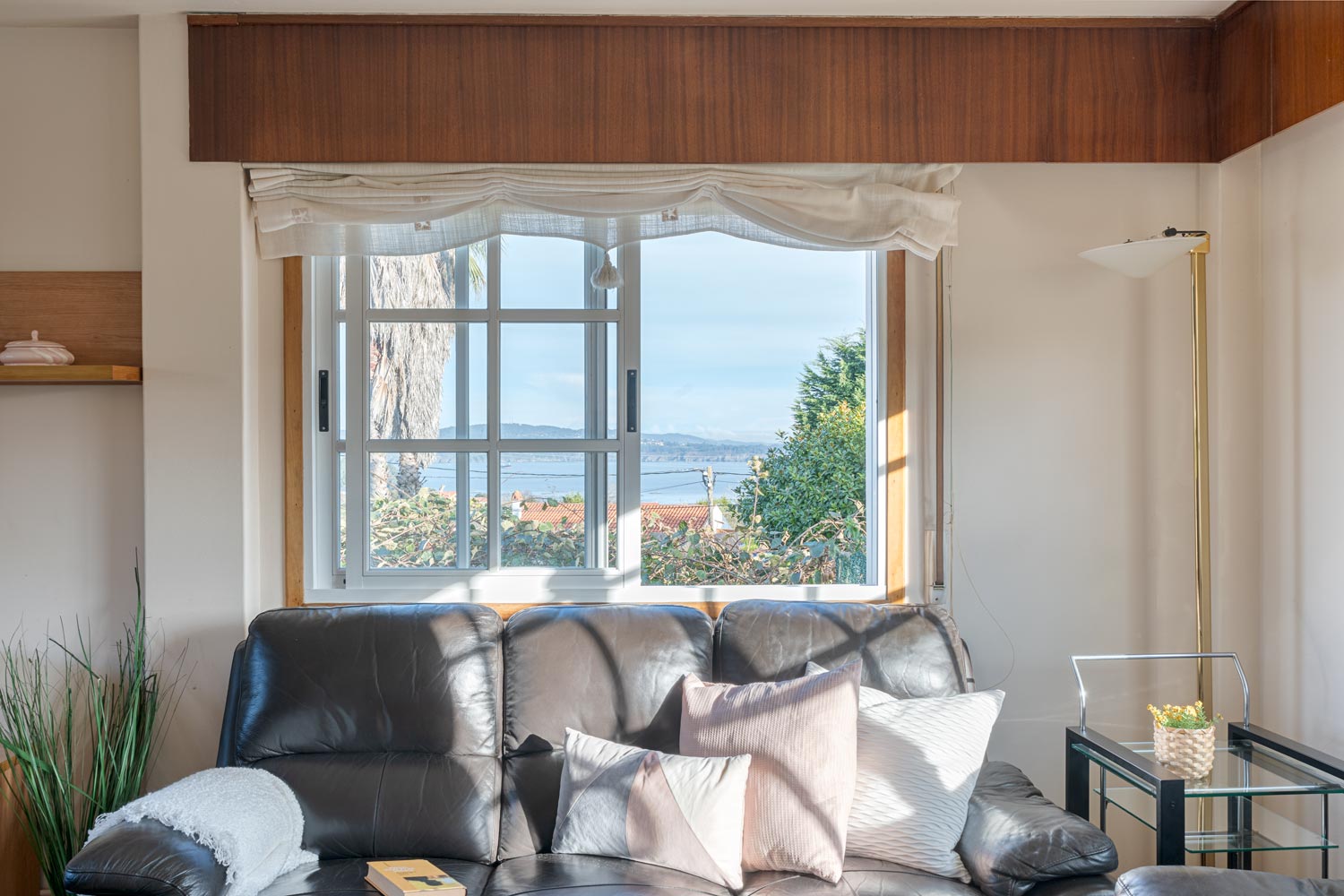 Sala de estar luminosa con sofás de cuero y ventana con vistas al mar en casa a la venta en Sada.