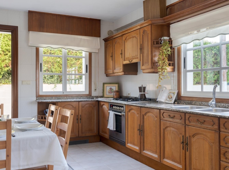 Cocina rústica de madera con encimera de granito y grandes ventanas en casa en venta en Sada.