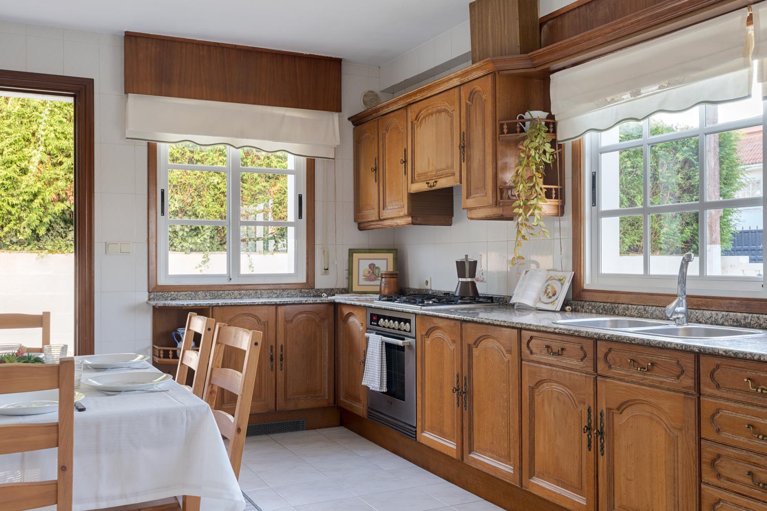 Cocina rústica de madera con encimera de granito y grandes ventanas en casa en venta en Sada.