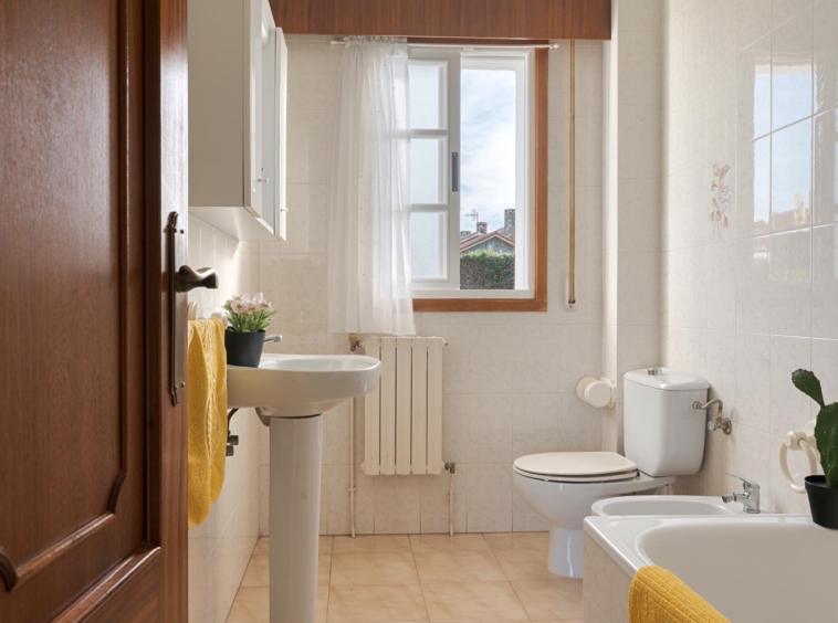 Baño con decoración clásica, bañera, lavabo y ventana luminosa en casa en venta en Sada.