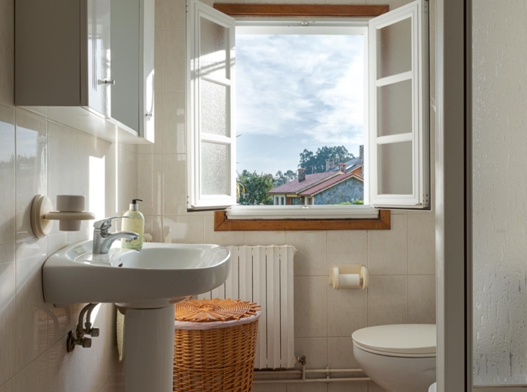 Baño con ventana abierta y vistas, lavabo y detalles decorativos en casa en venta en Sada.