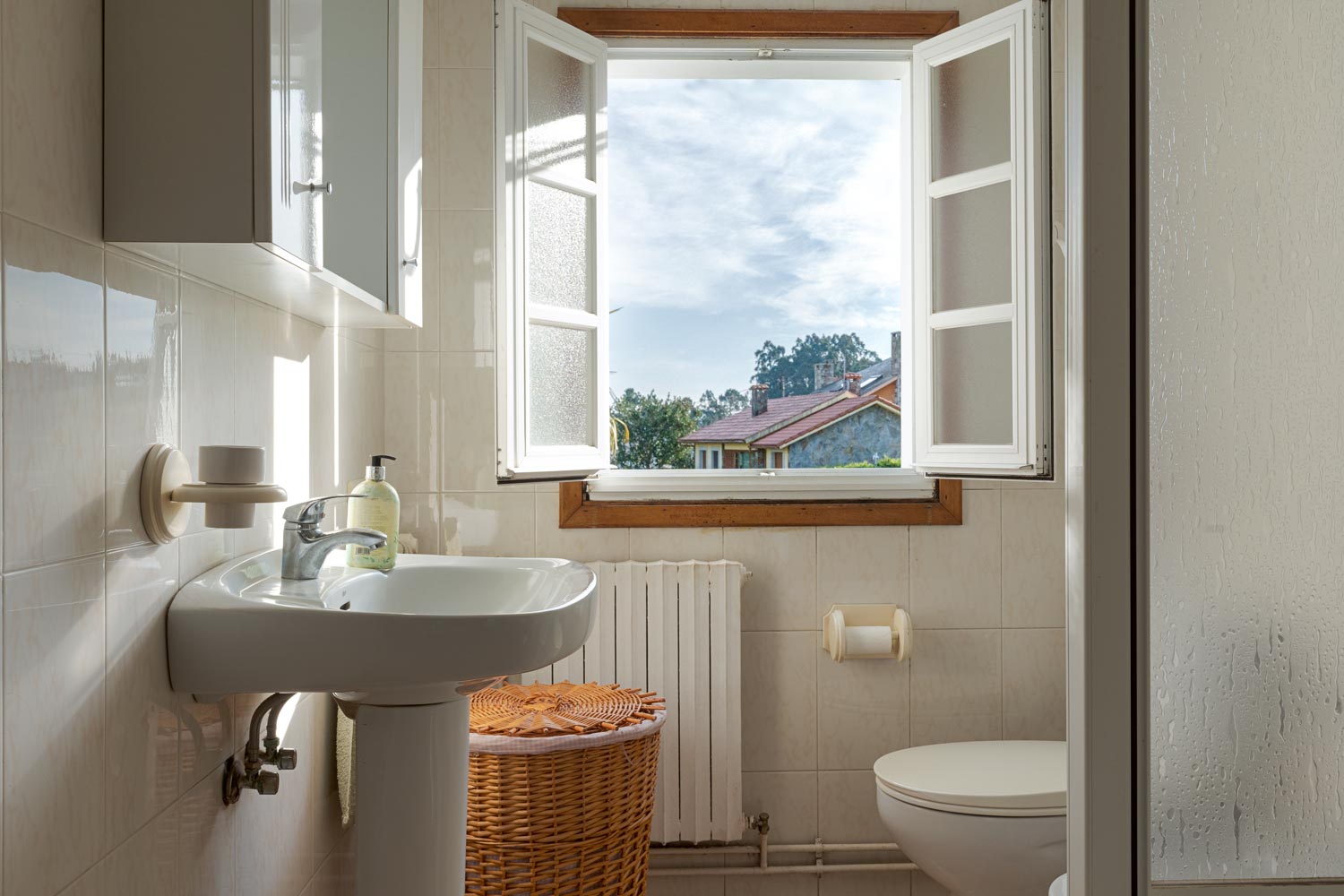 Baño con ventana abierta y vistas, lavabo y detalles decorativos en casa en venta en Sada.